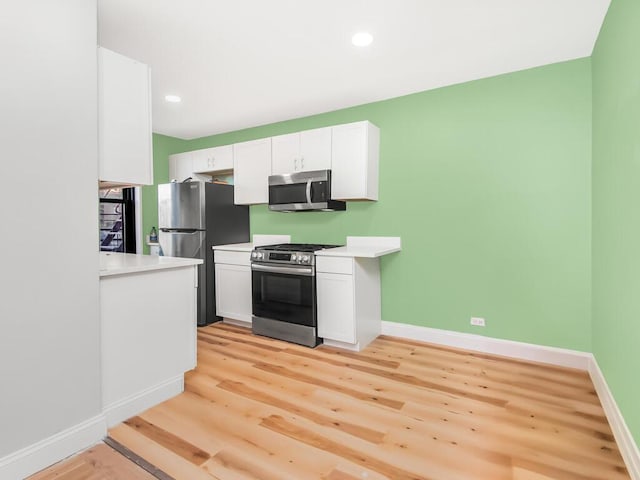 kitchen featuring stainless steel appliances, white cabinets, and light wood-type flooring