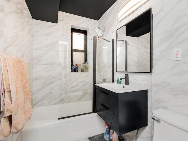 full bathroom featuring tile walls, vanity, tiled shower / bath combo, and toilet