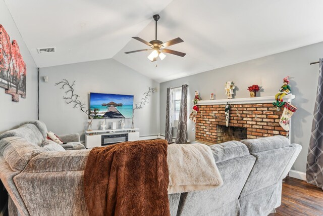 living room featuring dark wood-type flooring, ceiling fan, vaulted ceiling, and a brick fireplace