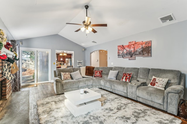 living room with a brick fireplace, ceiling fan with notable chandelier, vaulted ceiling, and dark hardwood / wood-style floors