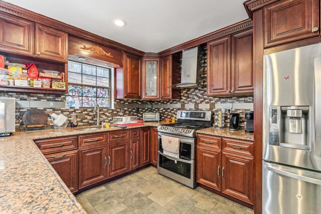 kitchen featuring tasteful backsplash, sink, light stone counters, stainless steel appliances, and wall chimney range hood