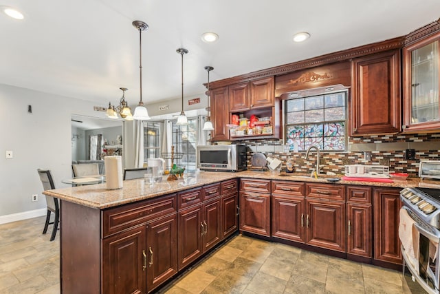 kitchen featuring sink, light stone counters, decorative light fixtures, stainless steel appliances, and backsplash