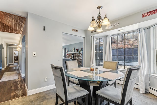 dining area featuring an inviting chandelier and a brick fireplace