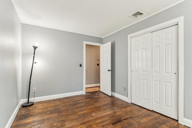 unfurnished bedroom featuring ornamental molding, dark hardwood / wood-style flooring, and a closet