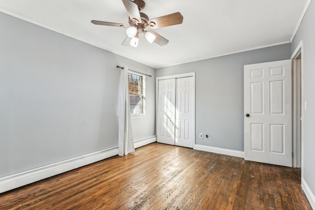 unfurnished bedroom with dark wood-type flooring, crown molding, a baseboard radiator, a closet, and ceiling fan