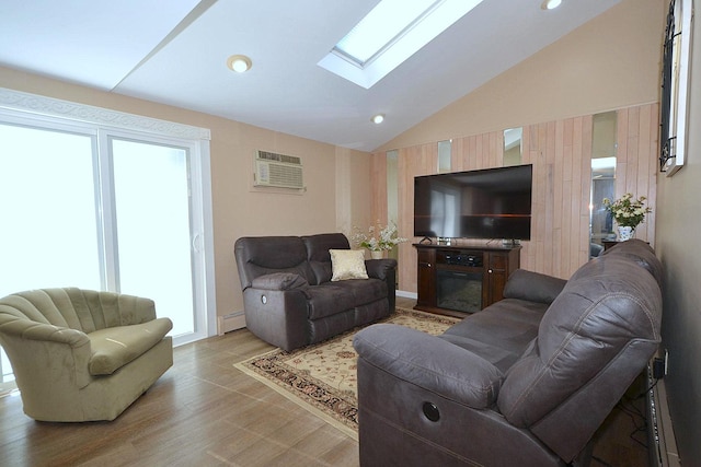 living room featuring baseboard heating, a wall mounted air conditioner, vaulted ceiling with skylight, and light wood-type flooring