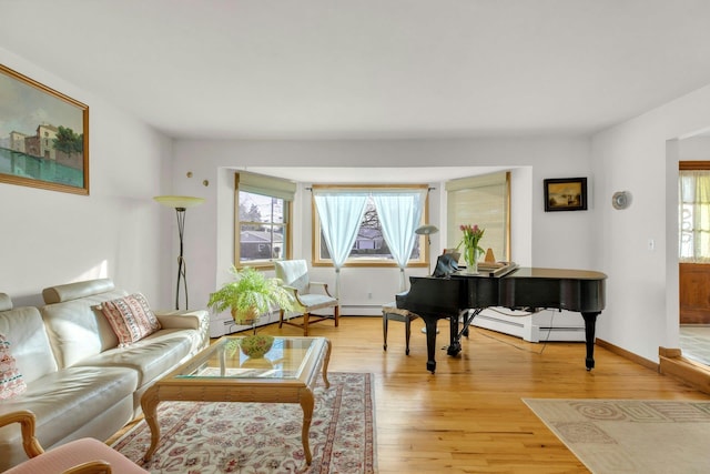 living room with a wealth of natural light, light wood-type flooring, and baseboard heating