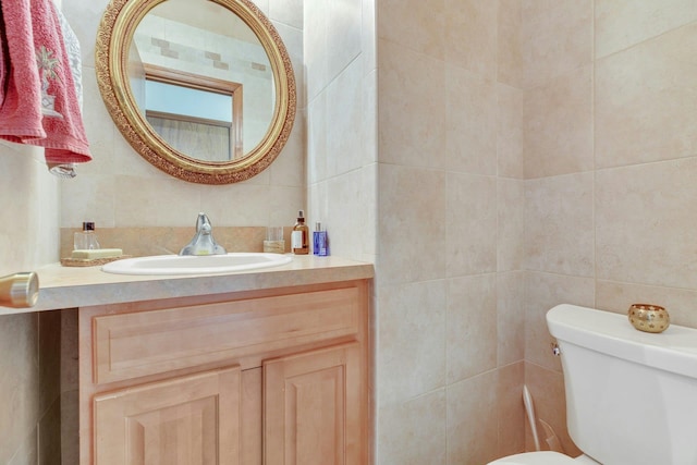 bathroom with vanity, tile walls, and toilet