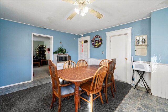 dining space featuring dark colored carpet and ceiling fan