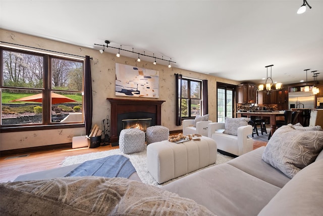 79 Victor Dr, Poughkeepsie, NY 12603 - living area featuring a glass covered fireplace, light wood-type flooring, track lighting, an inviting chandelier, and baseboards