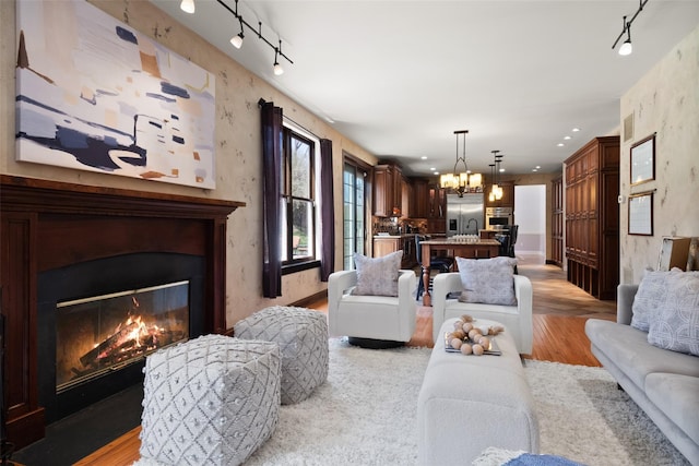 79 Victor Dr, Poughkeepsie, NY 12603 - living area with a glass covered fireplace, track lighting, light wood-style flooring, a notable chandelier, and recessed lighting