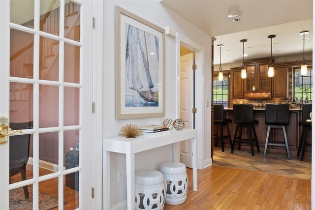 79 Victor Dr, Poughkeepsie, NY 12603 - interior space with brown cabinetry, a breakfast bar, glass insert cabinets, light wood finished floors, and decorative light fixtures