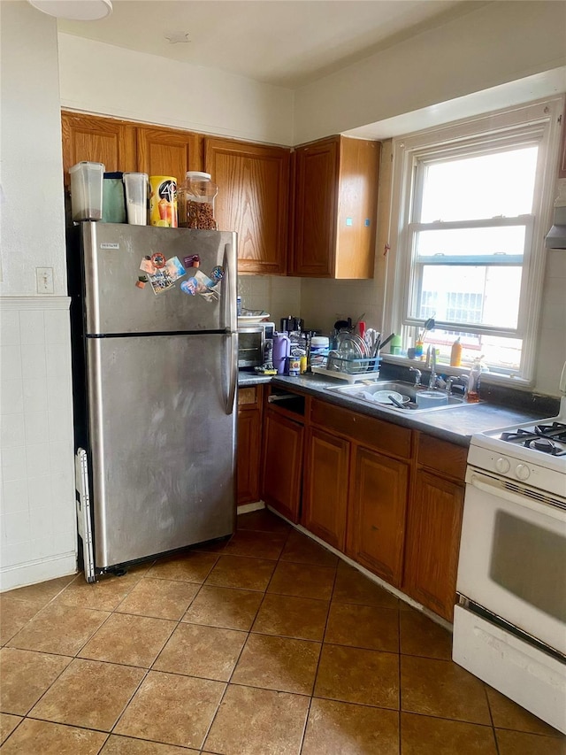 kitchen featuring tile patterned floors, stainless steel fridge, sink, and gas range gas stove