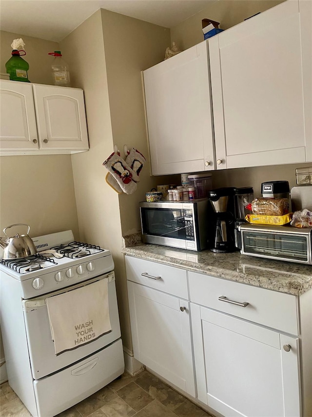 kitchen featuring white range with gas cooktop and white cabinets