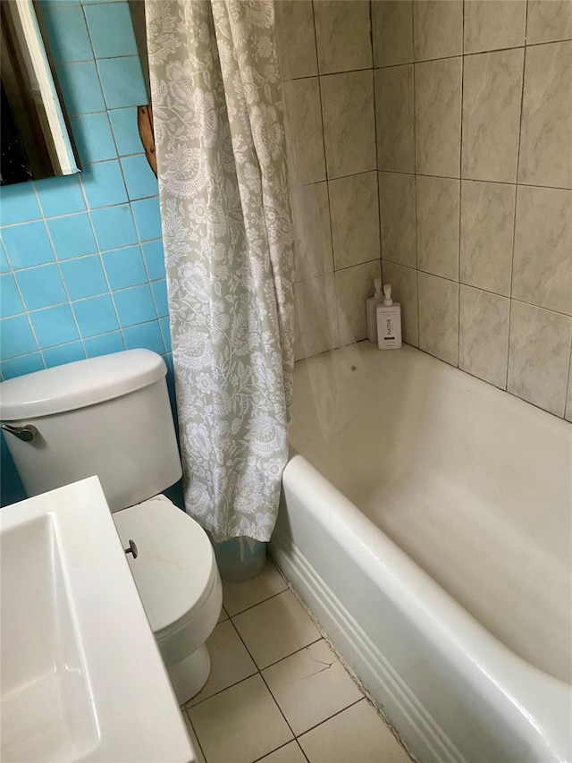 full bathroom with sink, tile walls, toilet, tile patterned floors, and shower / bath combo with shower curtain