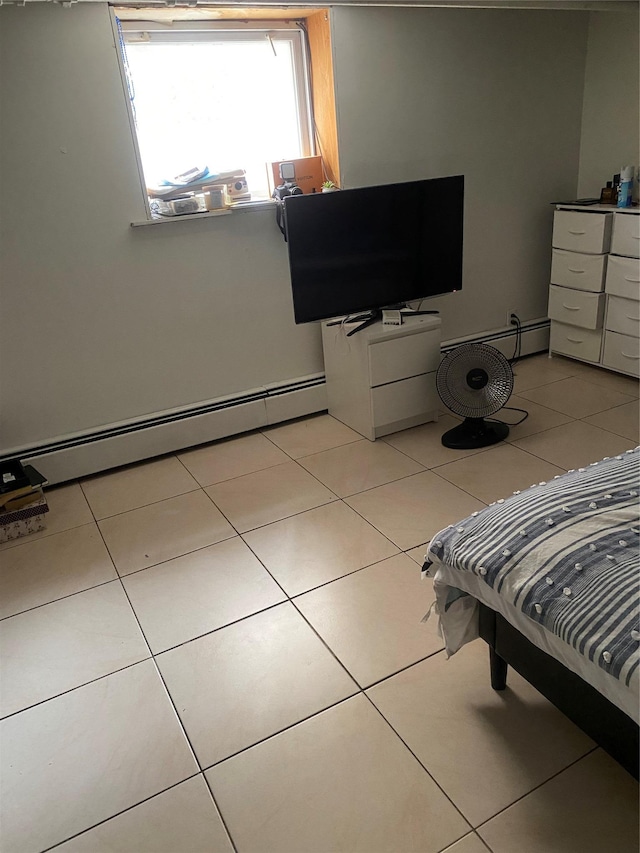 bedroom with a baseboard heating unit and light tile patterned floors