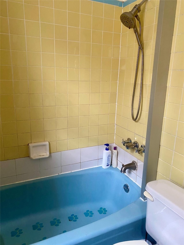 bathroom with tiled shower / bath combo and toilet