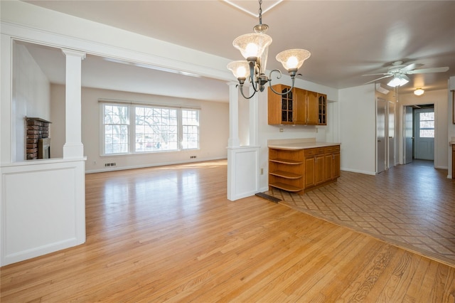 unfurnished dining area featuring plenty of natural light, decorative columns, and light wood-type flooring