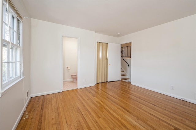 unfurnished bedroom featuring ensuite bath and light hardwood / wood-style flooring