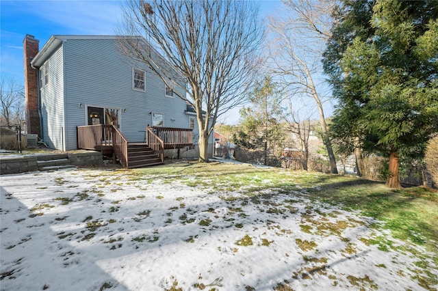 yard layered in snow with a wooden deck and central AC