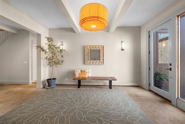 entryway with beam ceiling, stone finish flooring, and baseboards