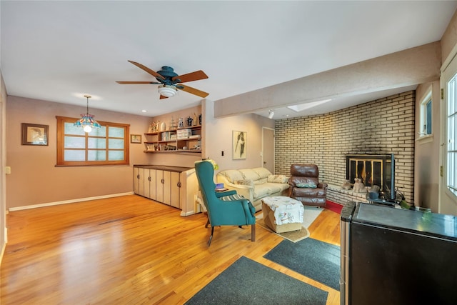 living room featuring hardwood / wood-style floors, a fireplace, ceiling fan, and plenty of natural light