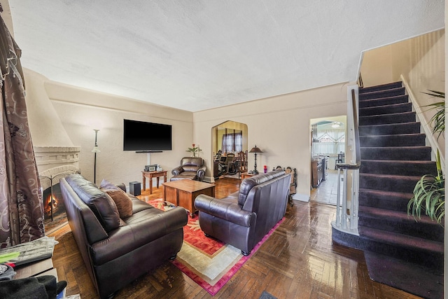 living room featuring dark parquet flooring, a textured ceiling, and a fireplace