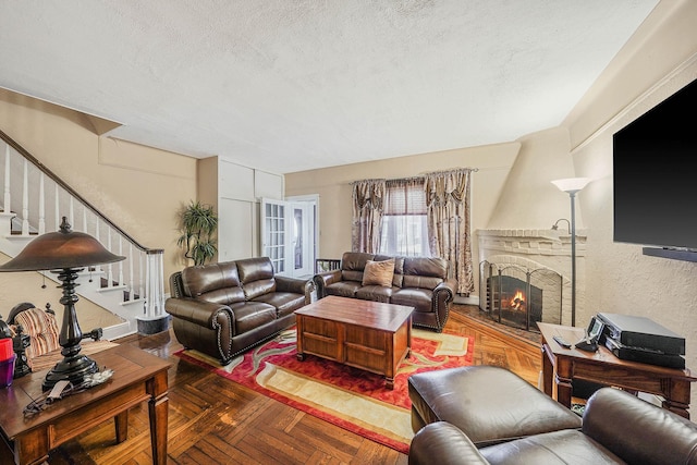 living room featuring parquet flooring, a fireplace, and a textured ceiling