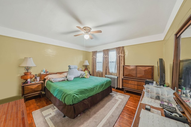 bedroom with dark wood-type flooring, ceiling fan, and radiator