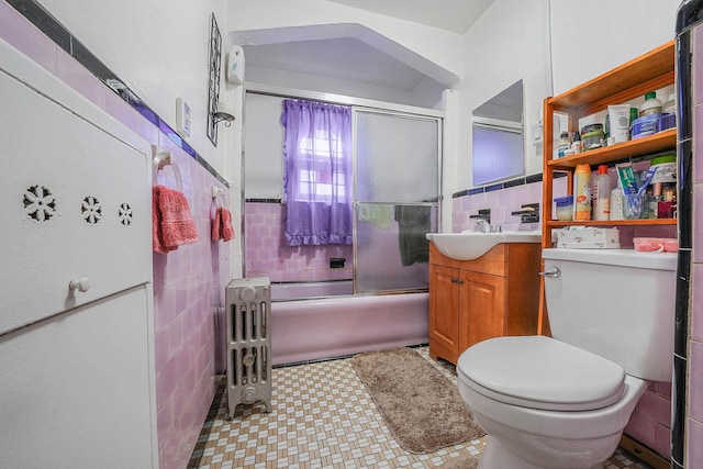 full bathroom featuring radiator, tile walls, shower / bath combination with glass door, vanity, and toilet