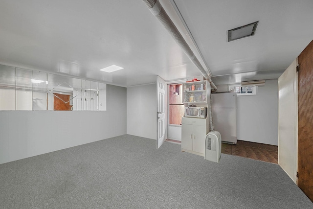 basement with white refrigerator and dark carpet