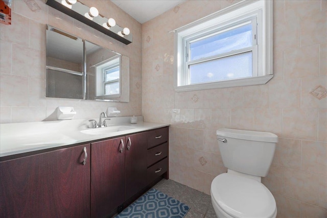 bathroom featuring a healthy amount of sunlight, toilet, and tile walls