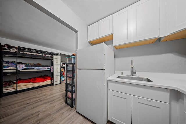 kitchen featuring sink, light hardwood / wood-style floors, white cabinets, and white refrigerator