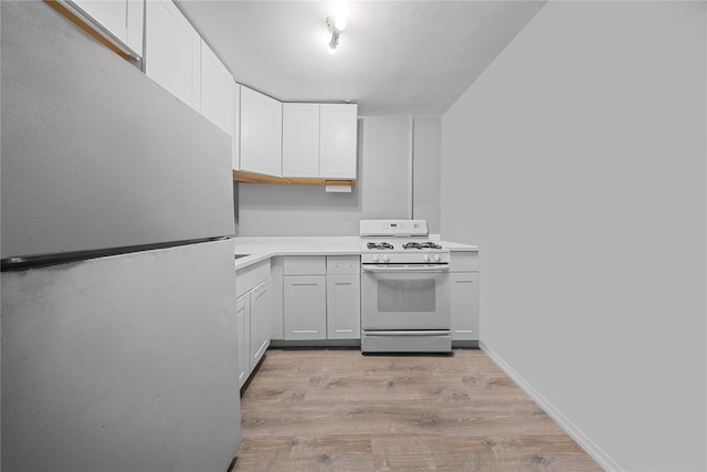 kitchen with stainless steel refrigerator, white cabinetry, light hardwood / wood-style floors, and gas range gas stove