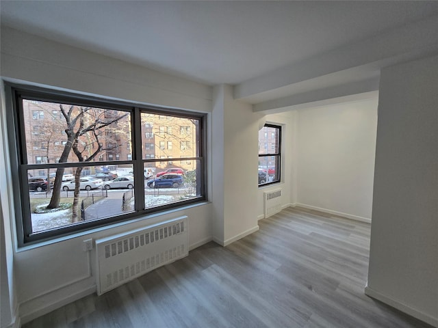 spare room with hardwood / wood-style floors and radiator heating unit