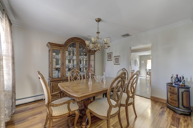 dining room with crown molding, a baseboard heating unit, a notable chandelier, and light hardwood / wood-style flooring