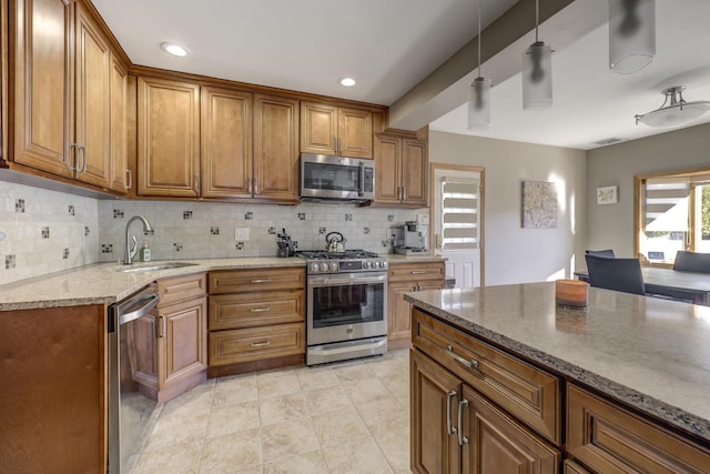 kitchen with tasteful backsplash, sink, hanging light fixtures, stainless steel appliances, and light stone countertops