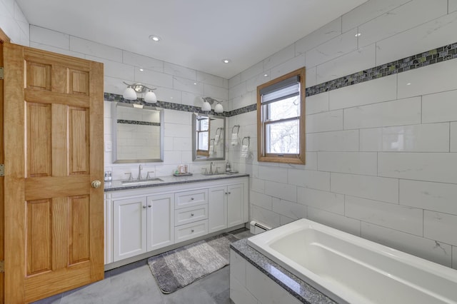 bathroom featuring baseboard heating, vanity, tiled bath, and tile walls