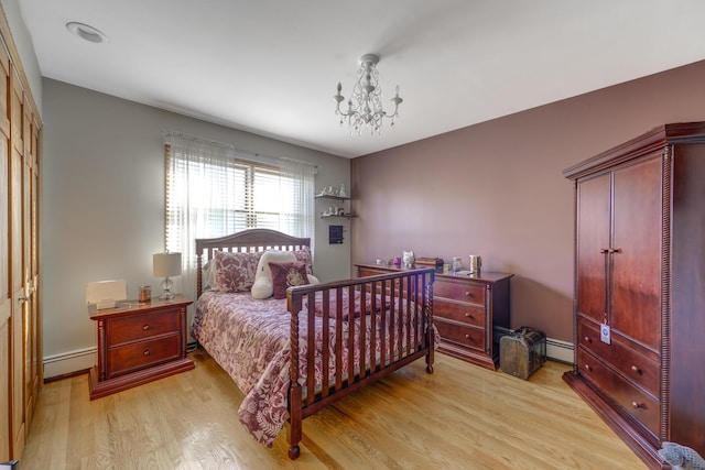 bedroom with a baseboard heating unit, a chandelier, and light hardwood / wood-style floors