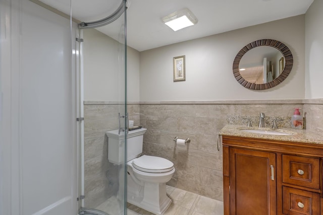 bathroom with tile patterned floors, toilet, an enclosed shower, tile walls, and vanity