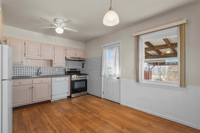 kitchen with sink, white appliances, decorative light fixtures, and dark hardwood / wood-style floors