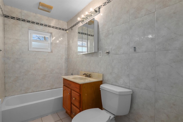 bathroom with a wealth of natural light, tile walls, tile patterned flooring, vanity, and toilet