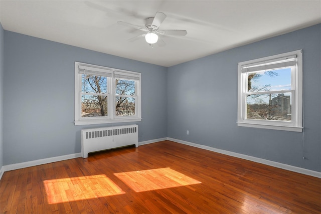 spare room featuring hardwood / wood-style flooring, radiator heating unit, and ceiling fan