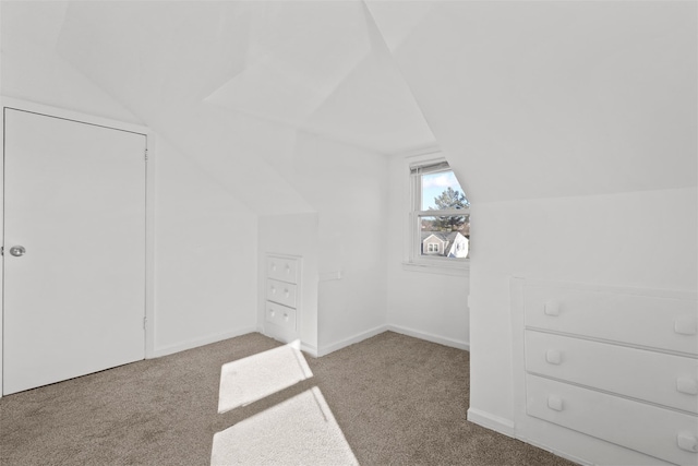 bonus room with lofted ceiling and light carpet