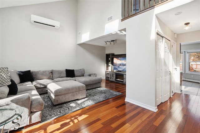 living room featuring dark hardwood / wood-style flooring, a towering ceiling, a baseboard radiator, and an AC wall unit