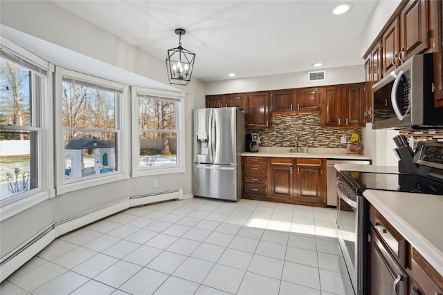 kitchen featuring sink, light tile patterned floors, hanging light fixtures, stainless steel appliances, and decorative backsplash