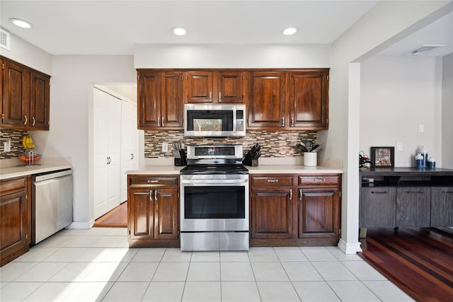 kitchen with light tile patterned floors, decorative backsplash, and stainless steel appliances