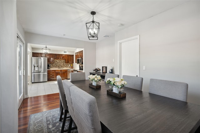 dining area with sink, light hardwood / wood-style flooring, and a notable chandelier