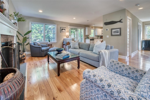 living room with light hardwood / wood-style floors and a brick fireplace