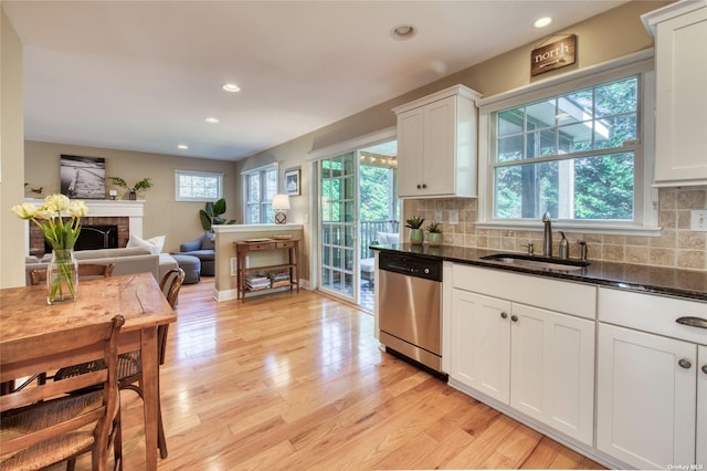 kitchen with white cabinetry, a brick fireplace, sink, and stainless steel dishwasher